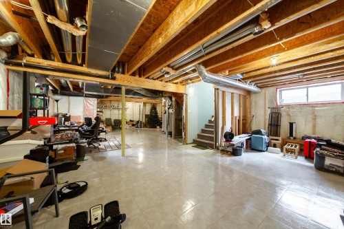 Expansive unfinished basement featuring an open floor plan, exposed wood joists, tile flooring, and a framed staircase - 2016 125 Street, Edmonton, AB - Indoor Photo Showing Basement