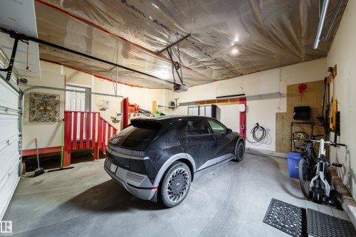 Spacious garage featuring a concrete floor, built-in storage cabinetry, overhead lighting, and a dedicated EV charging station - 2016 125 Street, Edmonton, AB - Indoor Photo Showing Garage