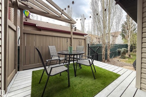 Outdoor patio featuring a pergola, string lights, artificial turf, wood-finish decking, and a privacy fence - 2016 125 Street, Edmonton, AB - Outdoor With Deck Patio Veranda With Exterior