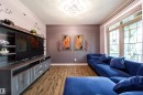 Living area featuring wood-finish flooring, a contemporary ceiling light fixture, a built-in media console with open shelving and drawers, large multi-pane windows, and a neutral wall color palette - 2016 125 Street, Edmonton, AB  - Indoor 