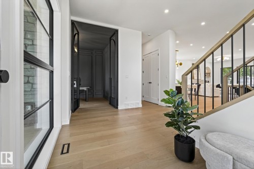Light wood-finish flooring extends through an entryway featuring a black metal and glass front door - 13804 85 Avenue, Edmonton, AB - Indoor Photo Showing Other Room