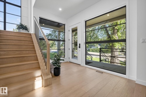 Entryway featuring light wood-finish flooring, a contemporary staircase with wood treads and black metal balusters, and a full-light entry door - 13804 85 Avenue, Edmonton, AB - Indoor Photo Showing Other Room