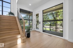 Entryway featuring light wood-finish flooring, a contemporary staircase with wood treads and black metal balusters, and a full-light entry door - 