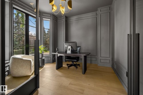 Dedicated interior space featuring light wood-finish flooring, dark paneled walls with detailed molding, and large window panels with dark framing - 13804 85 Avenue, Edmonton, AB - Indoor Photo Showing Office