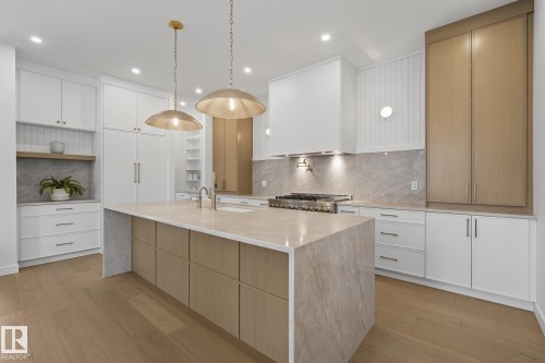 Kitchen featuring a large central island with a stone-finish countertop, wood-finish cabinetry, and under-counter storage - 13804 85 Avenue, Edmonton, AB - Indoor Photo Showing Kitchen With Upgraded Kitchen