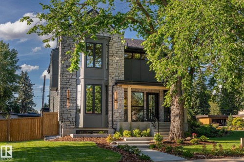 Stone and siding exterior with a covered front porch featuring a dark entry door and sidelights - 13804 85 Avenue, Edmonton, AB - Outdoor