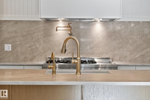Kitchen featuring a gold-finish gooseneck faucet, integrated sink, and a contrasting light wood-finish countertop - 13804 85 Avenue, Edmonton, AB - Indoor Photo Showing Kitchen