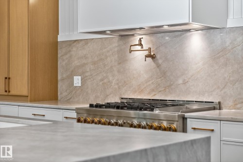 Gourmet kitchen featuring a professional-grade gas range, full-height stone backsplash, and a brass pot filler - 13804 85 Avenue, Edmonton, AB - Indoor Photo Showing Other Room