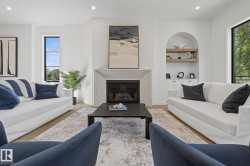 Spacious interior featuring light wood-finish flooring, a contemporary fireplace with a stone-finish mantle, large windows, and a built-in arched alcove with shelving and lower cabinetry - 