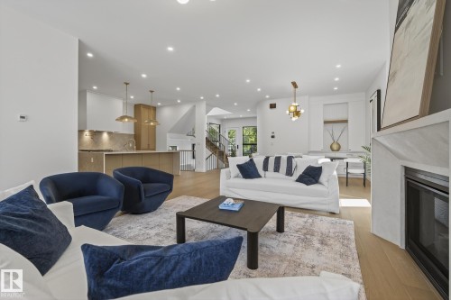 Spacious living area featuring light wood-finish flooring, recessed lighting, and a modern fireplace with a light-toned surround - 13804 85 Avenue, Edmonton, AB - Indoor Photo Showing Living Room