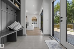 Foyer featuring large format tile flooring, built-in bench with beadboard detailing, integrated shelving, and a full-light entry door leading to an exterior deck - 