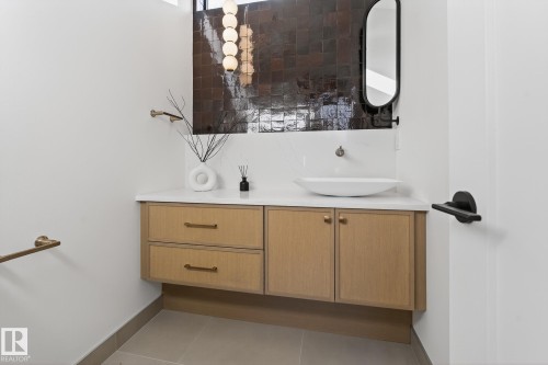 Floating wood-finish vanity with two drawers and two cabinet doors, topped with a white countertop and vessel sink - 13804 85 Avenue, Edmonton, AB - Indoor Photo Showing Bathroom