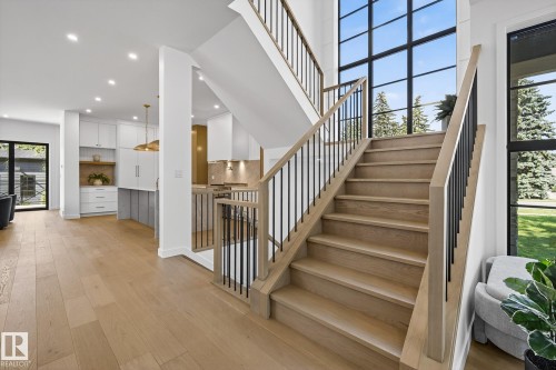 Modern staircase with light wood-finish treads and risers, featuring a black metal spindle railing and natural wood handrail - 13804 85 Avenue, Edmonton, AB - Indoor Photo Showing Other Room