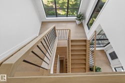 Multi-level light wood staircase featuring black metal balusters and light wood handrails - 