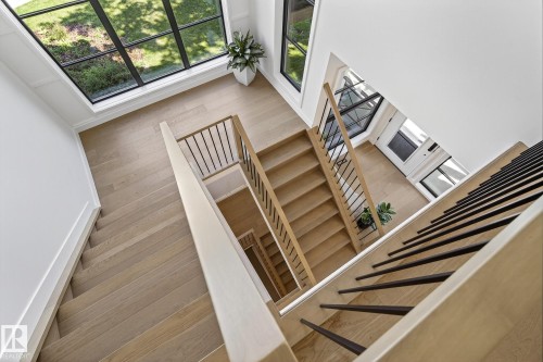 Multi-level interior staircase featuring light wood-finish treads and risers, contemporary black metal balusters, and a solid wood handrail - 13804 85 Avenue, Edmonton, AB - Indoor Photo Showing Other Room