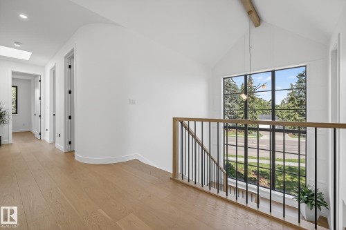 Two-story window featuring black framing, a vaulted ceiling with a modern pendant light fixture, and light wood-finish flooring - 13804 85 Avenue, Edmonton, AB - Indoor Photo Showing Other Room