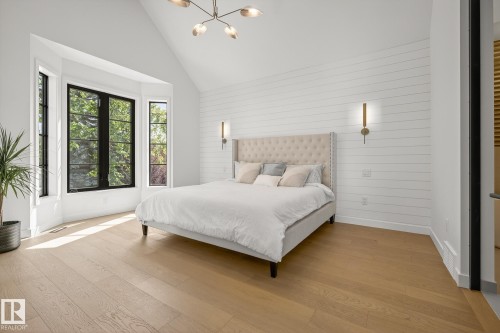 Vaulted ceiling room featuring a bay window with black trim, wood-finish flooring, shiplap accent wall, and contemporary wall sconces - 13804 85 Avenue, Edmonton, AB - Indoor Photo Showing Bedroom