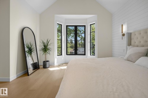 Vaulted ceiling room featuring light wood-finish flooring, a prominent bay window with black-framed panes, and a shiplap accent wall - 13804 85 Avenue, Edmonton, AB - Indoor Photo Showing Bedroom