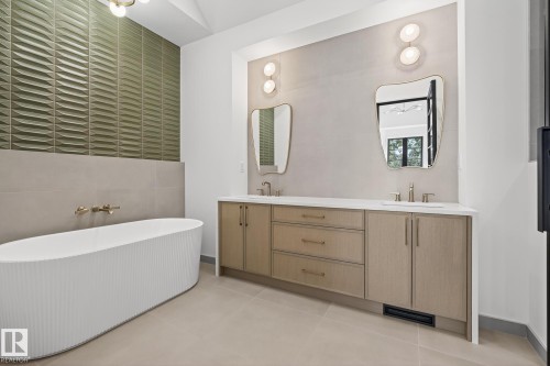 Freestanding fluted bathtub with wall-mounted brass fixtures, set against a textured green accent wall - 13804 85 Avenue, Edmonton, AB - Indoor Photo Showing Bathroom