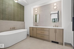 Freestanding fluted bathtub with wall-mounted brass fixtures, set against a textured green accent wall - 