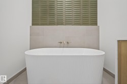 Freestanding bathtub with a fluted exterior, accompanied by wall-mounted brass fixtures - 
