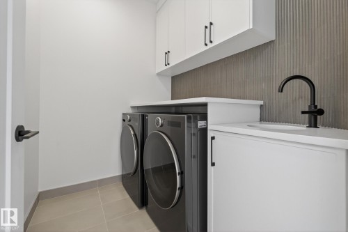 Laundry area featuring a large basin sink with a matte black faucet, white cabinetry, and a textured vertical tile backsplash - 13804 85 Avenue, Edmonton, AB - Indoor Photo Showing Laundry Room
