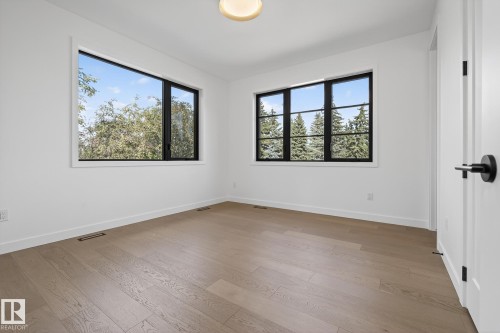 Spacious room featuring light wood-finish flooring, white walls, and a contemporary ceiling light fixture - 13804 85 Avenue, Edmonton, AB - Indoor Photo Showing Other Room