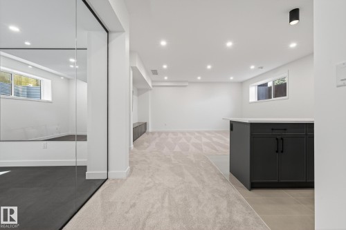 Spacious lower-level area featuring recessed lighting, a built-in dark cabinetry unit with a light-toned countertop, and two egress windows - 13804 85 Avenue, Edmonton, AB - Indoor Photo Showing Other Room