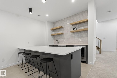 Entertainment bar area featuring a light-toned backsplash, floating wood shelving, and a built-in beverage refrigerator - 13804 85 Avenue, Edmonton, AB - Indoor Photo Showing Other Room