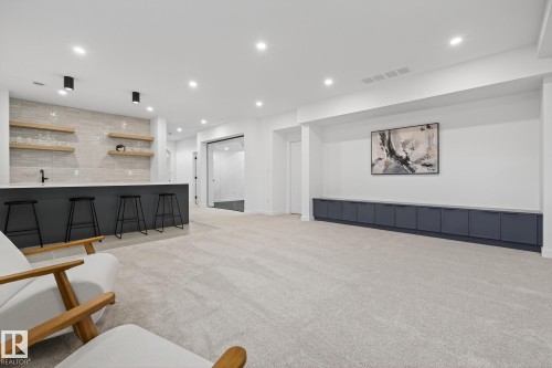 Spacious finished room featuring a built-in wet bar with a light grey tiled backsplash and floating wood shelving - 13804 85 Avenue, Edmonton, AB - Indoor Photo Showing Kitchen