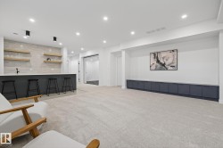 Spacious finished room featuring a built-in wet bar with a light grey tiled backsplash and floating wood shelving - 