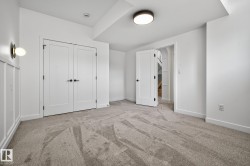 Carpeted room featuring a ceiling-mounted light fixture, recessed smoke detector, and white baseboards - 
