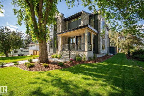 Contemporary exterior featuring stone cladding, large windows, an inviting covered entry with columns, concrete steps, and dark metal railings - 13804 85 Avenue, Edmonton, AB - Outdoor