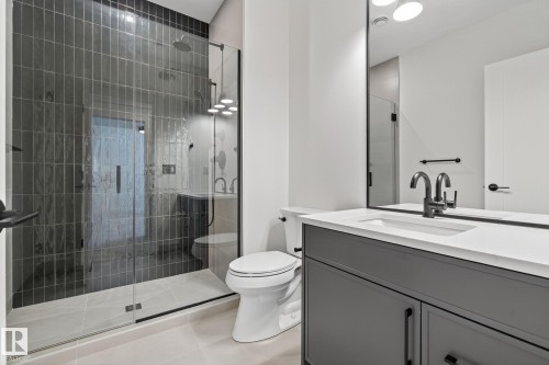 Modern bathroom featuring a frameless glass shower enclosure with dark vertical tile, a rain shower head, and a multi-jet shower system - 13804 85 Avenue, Edmonton, AB - Indoor Photo Showing Bathroom