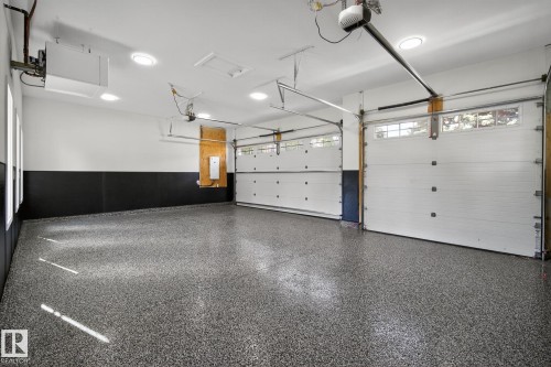 Spacious garage featuring a durable epoxy floor, white walls with a black wainscoting, and multiple recessed ceiling lights - 13804 85 Avenue, Edmonton, AB - Indoor Photo Showing Garage