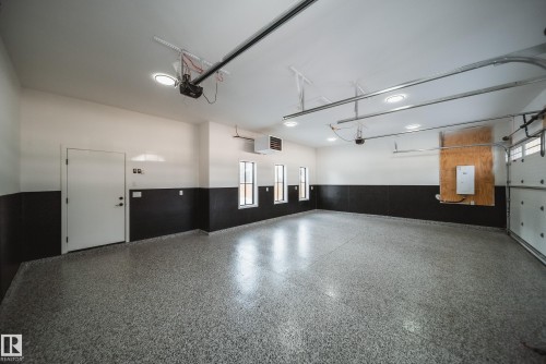 Spacious garage with an epoxy-coated floor, multiple flush-mount ceiling lights, three vertical windows, and a built-in wall heater - 13804 85 Avenue, Edmonton, AB - Indoor Photo Showing Garage