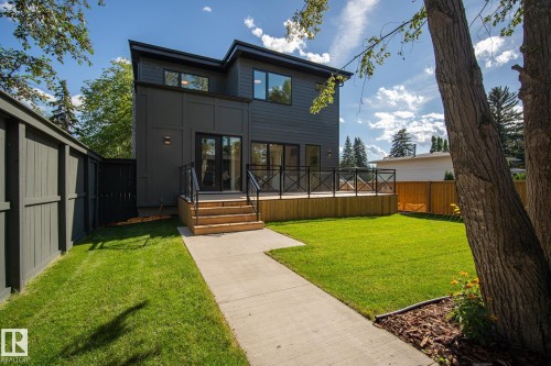 Contemporary two-story exterior with dark gray siding, a spacious wood deck, and a manicured lawn - 13804 85 Avenue, Edmonton, AB - Outdoor