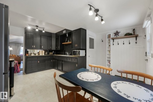 Kitchen featuring extensive dark cabinetry, track lighting, and light-toned flooring - 5043 48 St Nw, Sylvan Lake, AB - Indoor