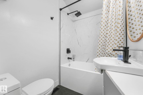 Contemporary bathroom featuring a white soaking tub with marble-look tile surround and matte black fixtures - 5043 48 St Nw, Sylvan Lake, AB - Indoor Photo Showing Bathroom