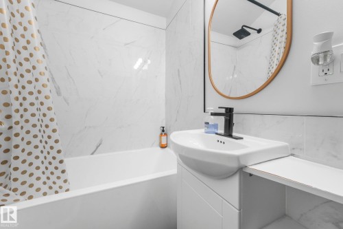 Contemporary bathroom featuring a deep soaking tub with surrounding marble-look wall tile - 5043 48 St Nw, Sylvan Lake, AB - Indoor Photo Showing Bathroom