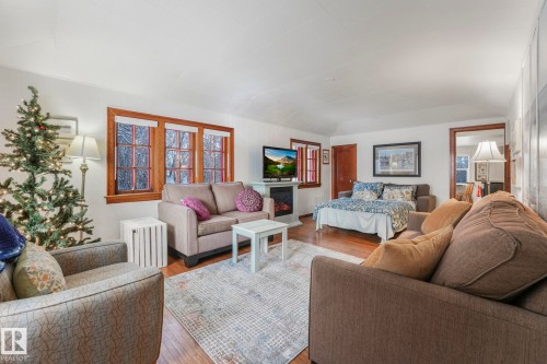 Open living space featuring wood-finish flooring, white walls, and a large area rug - 5043 48 St Nw, Sylvan Lake, AB - Indoor Photo Showing Living Room