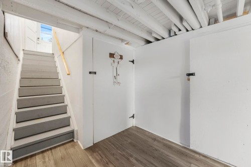 Finished basement area featuring wood-finish flooring, white painted walls, and an exposed beam ceiling - 5043 48 St Nw, Sylvan Lake, AB - Indoor Photo Showing Other Room