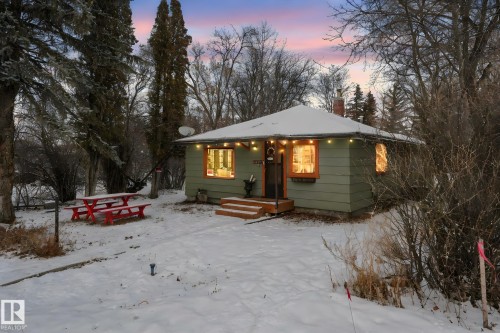 Charming single-story residence featuring a soft green exterior siding and a snow-covered gable roof - 5043 48 St Nw, Sylvan Lake, AB - Outdoor