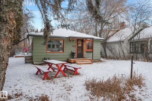 Green siding exterior with a dark-paneled entry door, wood trim accents, and a covered porch - 5043 48 St Nw, Sylvan Lake, AB - Outdoor