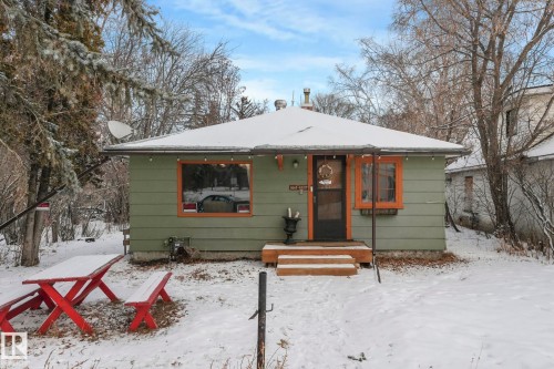 Single-story residence featuring light green siding and a snow-covered gable roof - 5043 48 St Nw, Sylvan Lake, AB - Outdoor