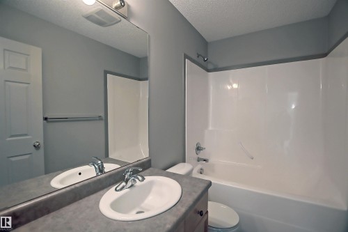 Bathroom featuring a vanity with an integrated sink, a large mirror, and a wall-mounted light fixture - 8129 7 Avenue, Edmonton, AB - Indoor Photo Showing Bathroom