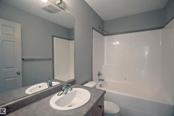 Bathroom featuring a vanity with an integrated sink, a large mirror, and a wall-mounted light fixture - 