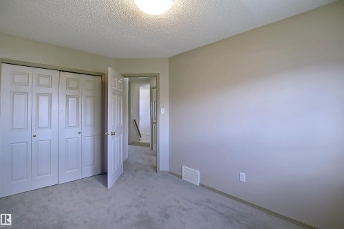 Bedroom featuring neutral-toned walls, light gray carpeting, and a textured ceiling - 8129 7 Avenue, Edmonton, AB - Indoor