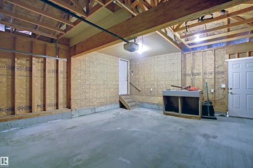 Spacious garage featuring exposed wood framing, concrete flooring, and a utility sink - 8129 7 Avenue, Edmonton, AB - Indoor Photo Showing Basement