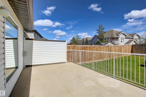 Concrete patio with white railing, featuring a manicured lawn and privacy fencing - 8129 7 Avenue, Edmonton, AB - Outdoor